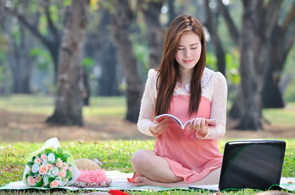 Femme assise sur un tapis de bois et un livre de lecture . — Photo