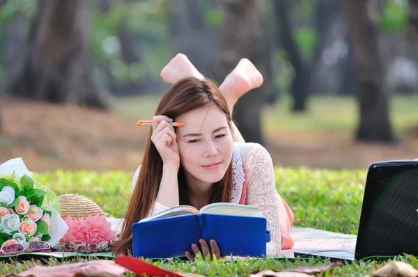 Frau sitzt auf Holzmatte und liest Buch. — Stockfoto