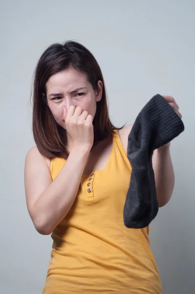 Retrato de mujer asiática en un vestido amarillo que huele calcetines asqueroso. —  Fotos de Stock