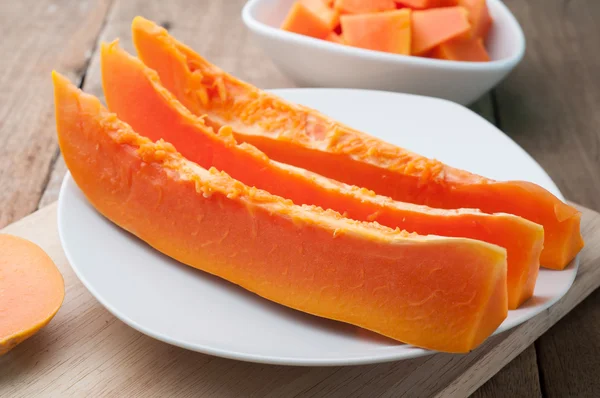 Papaya beyaz tabaklar ve ahşap arka plan dilimlenmiş.