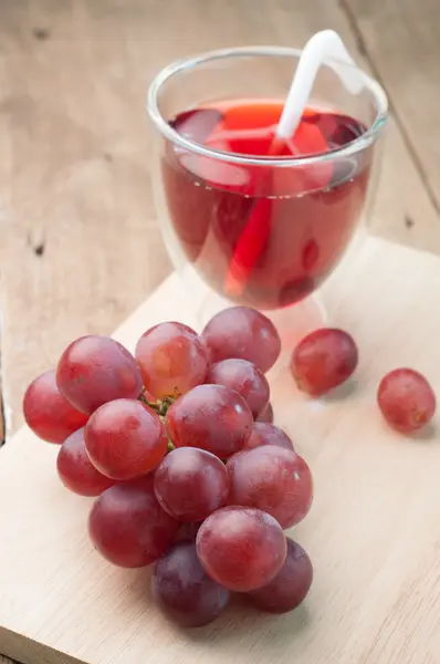 Purple grape juice in glass on a wood cutting boards. — Stock Photo, Image