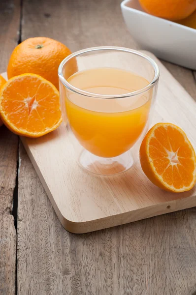 Vaso de zumo de naranja sobre tablas de cortar de madera . — Foto de Stock