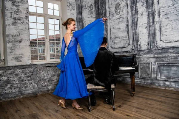 Молодий Чоловік Танцює Дівчиною Блакитній Бальній Сукні Сірому Танцювальному Залі — стокове фото