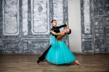 Dans kostümlü genç çift balo salonunda tango yapıyor.