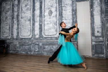 Dans kostümlü genç çift balo salonunda tango yapıyor.