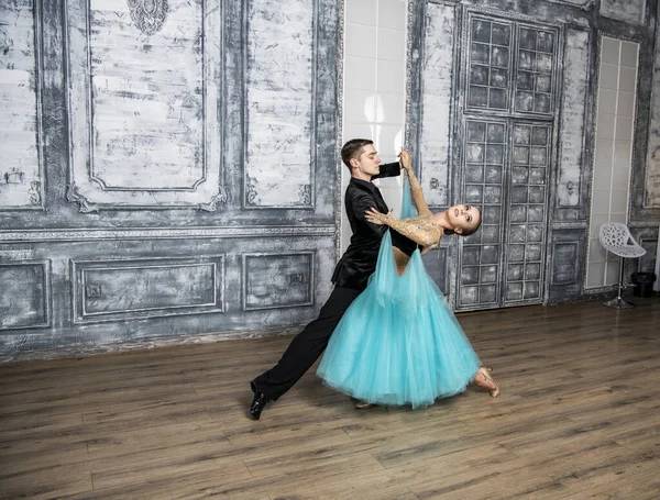 young couple in evening dance costumes dancing tango in the ballroom