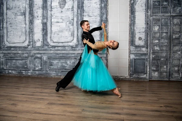 young couple in evening dance costumes dancing tango in the ballroom