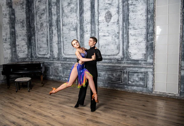 beautiful couple with dance costumes dancing latin dances in the hall