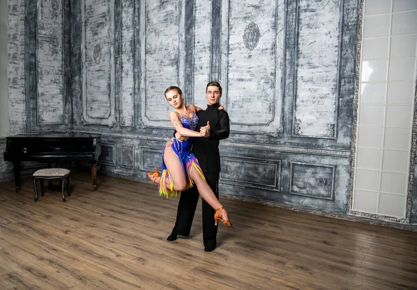 beautiful couple with dance costumes dancing latin dances in the hall