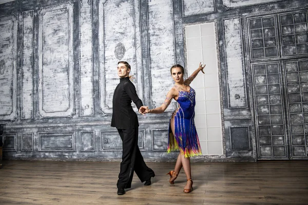 beautiful couple with dance costumes dancing latin dances in the hall