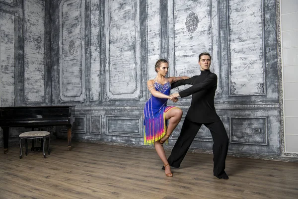 beautiful couple with dance costumes dancing latin dances in the hall