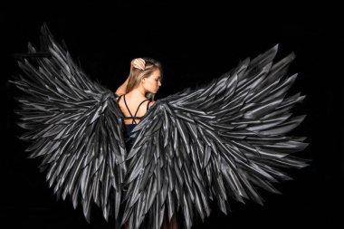 Siyah arka planda siyah kanatları olan siyah takım elbiseli güzel sarışın kız.