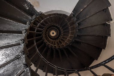 Denizdeki antik bir deniz fenerinde demir sarmal bir merdivenin çarpıcı geometrisi