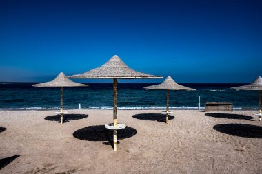 Şemsiyeli deniz kıyısı ve deniz zemininde mavi gökyüzü.