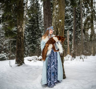 Rus güzeli ulusal bir kostüm içinde ve kışın karlı bir ormanda kızıl tilki 