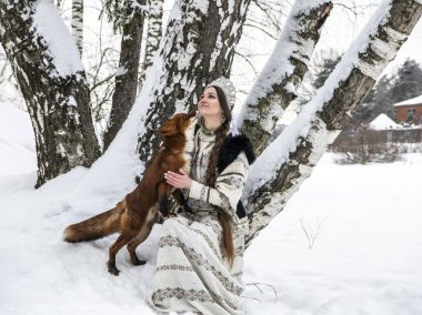 Ulusal kostümlü güzel bir Rus kızı ve kış ormanında kızıl bir tilki.