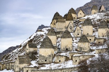 Osetya 'nın kar kaplı dağlarının arka planında antik taş kuleler ve harabeler var. 
