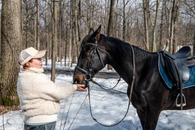 Bahar parkında siyah atlı, bej ceketli bir kadın. 