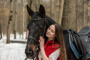 Beyaz elbiseli güzel bir kadın ve bahar ormanında siyah atlı kırmızı bir pelerin. 