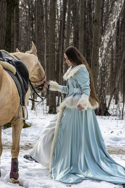 春の森の中の薄い茶色の馬と青いスーツの美しい女性 — ストック写真