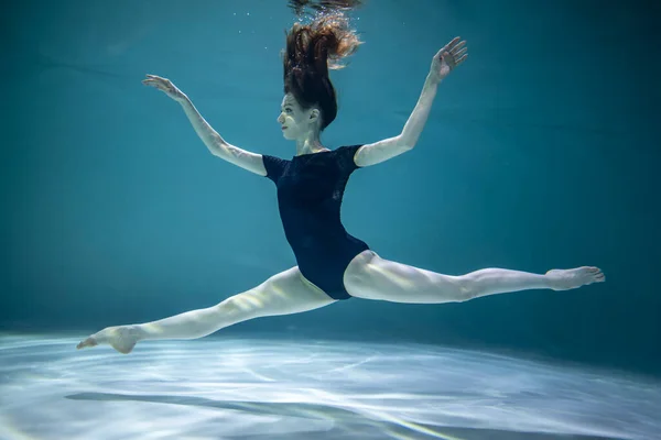 青い背景の下で水中で体操をする黒のヒョウの美しい女の子 — ストック写真