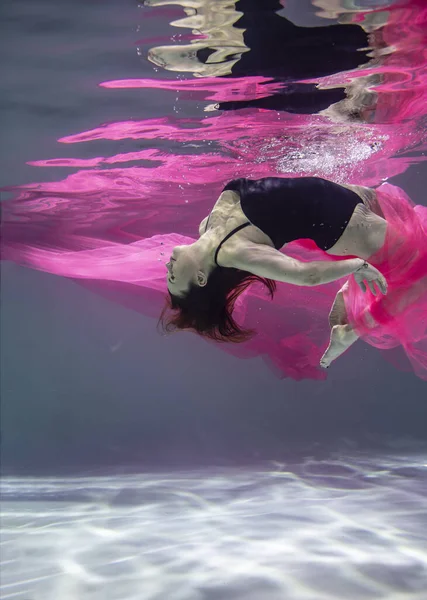 青い背景に赤いパレオの黒い水着を着た美しい女の子が水中で — ストック写真