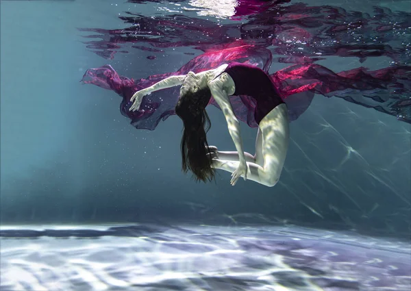 青い背景に水中に赤いパレオのある赤い水着の美しい女の子 — ストック写真