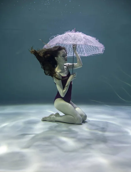 Mooi Meisje Een Rood Badpak Met Een Roze Paraplu Onderwater — Stockfoto