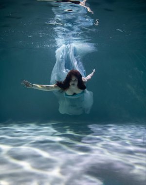 Mavi ve beyaz fayanslar içinde güzel bir kız mavi arka planda suyun altında
