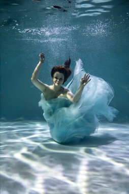 Mavi ve beyaz fayanslar içinde güzel bir kız mavi arka planda suyun altında