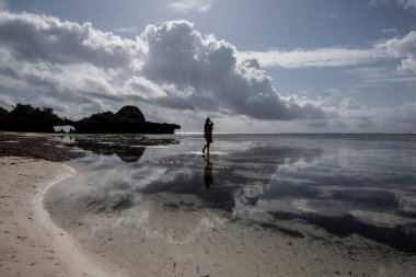 Mavi şapkalı kadın denizin alçak gelgiti sırasında mercan ve adaların arka planına poz veriyor. 