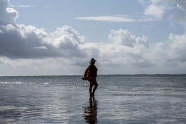 Mavi şapkalı kadın denizin alçak gelgiti sırasında mercan ve adaların arka planına poz veriyor. 