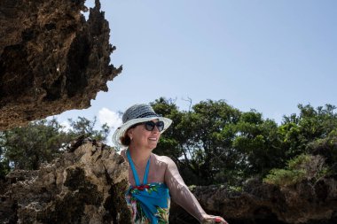 Mavi şapkalı kadın denizin alçak gelgiti sırasında mercan ve adaların arka planına poz veriyor. 