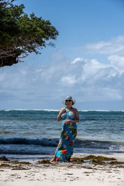 Mavi şapkalı kadın denizin alçak gelgiti sırasında mercan ve adaların arka planına poz veriyor. 