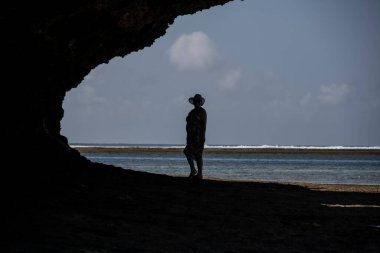 Mavi şapkalı kadın denizin alçak gelgiti sırasında mercan ve adaların arka planına poz veriyor. 