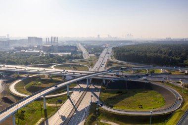 Sabahın erken saatlerinde insansız hava aracının yüksekliğinden yeşil ormanlar ve yollar arasındaki zarif kavşak. 