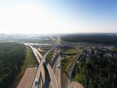 Sabahın erken saatlerinde insansız hava aracının yüksekliğinden yeşil ormanlar ve yollar arasındaki zarif kavşak. 
