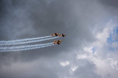 a group of combat aircraft perform complex aerobatics with a smoke launch against the sky