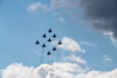 nine combat aircraft perform complex aerobatics against the sky 