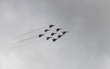 nine combat aircraft perform complex aerobatics against the sky 
