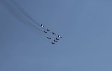 nine combat aircraft perform complex aerobatics against the sky 