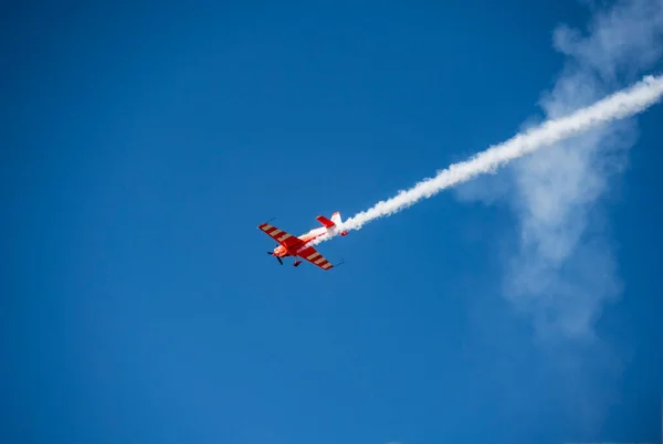 the red plane makes difficult turns and blows white smoke against the blue sky at the Max-21 aerospace salon in Zhukovsky on July 24, 2021