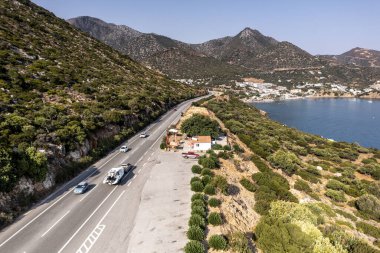 Deniz ve dağların panoramik görüntüsü ve bir drondan çekilen turkuaz su üzerindeki gemiler.