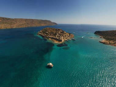 Spinalonga adasının panoramik görüntüsü. Gemiler ve turkuaz deniz insansız hava aracından çekiliyor. 