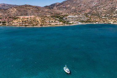 Deniz ve dağların panoramik görüntüsü ve bir drondan çekilen turkuaz su üzerindeki gemiler.