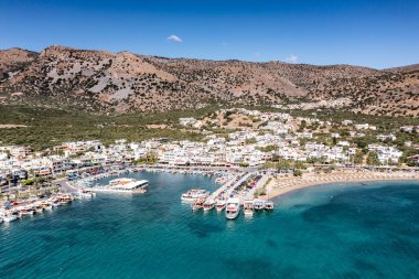 Deniz ve dağların panoramik görüntüsü ve bir drondan çekilen turkuaz su üzerindeki gemiler.