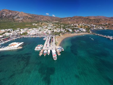 Deniz ve dağların panoramik görüntüsü ve bir drondan çekilen turkuaz su üzerindeki gemiler.
