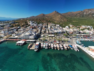 Deniz ve dağların panoramik görüntüsü ve bir drondan çekilen turkuaz su üzerindeki gemiler.