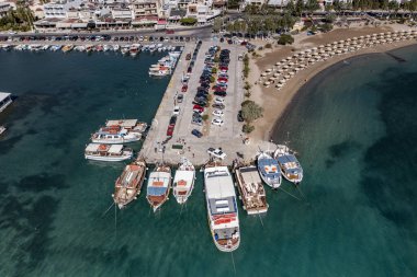Deniz ve dağların panoramik görüntüsü ve bir drondan çekilen turkuaz su üzerindeki gemiler.
