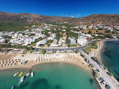 Deniz ve dağların panoramik görüntüsü ve bir drondan çekilen turkuaz su üzerindeki gemiler.